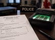 Criminal fingerprinting in Ontario appointment paperwork beside a fingerprint scanner